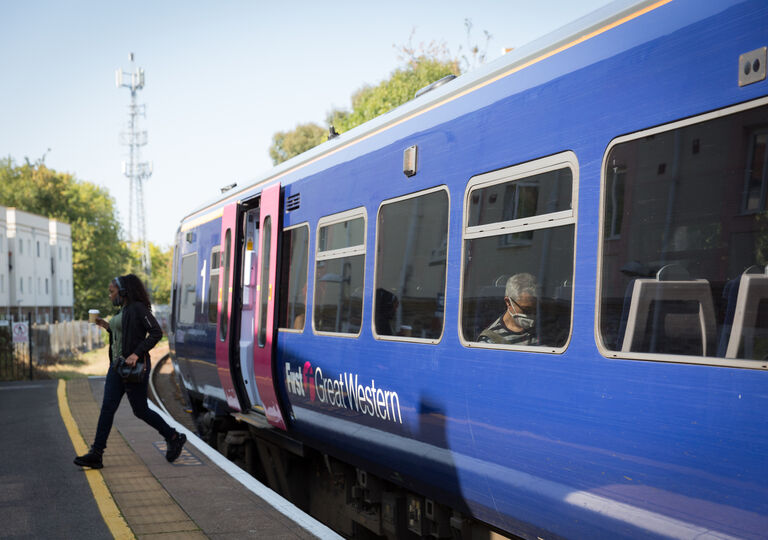 A lady exits a First Great Western train onto the platform