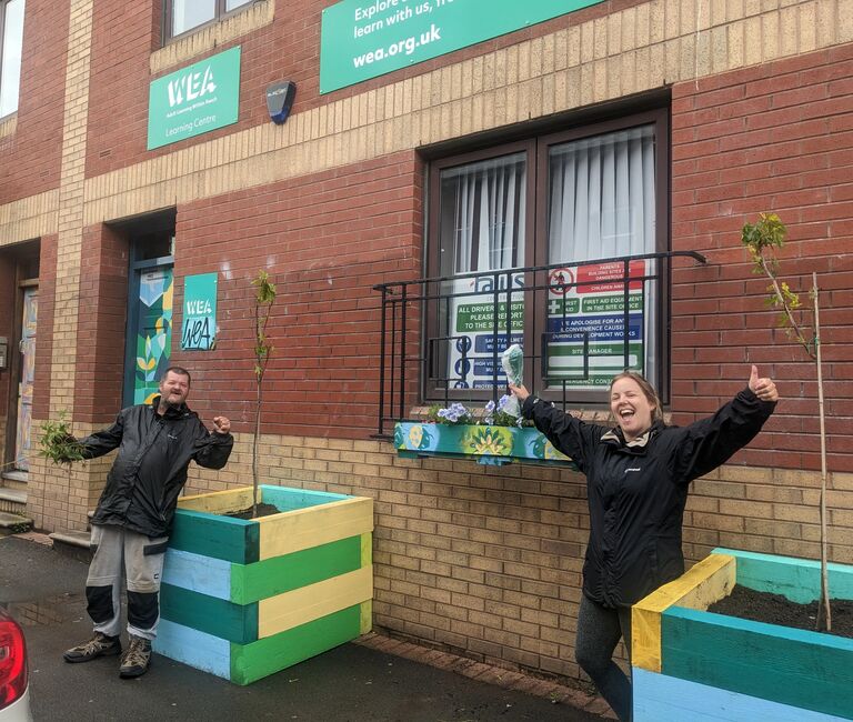 Two celebrating in front of WEA sign