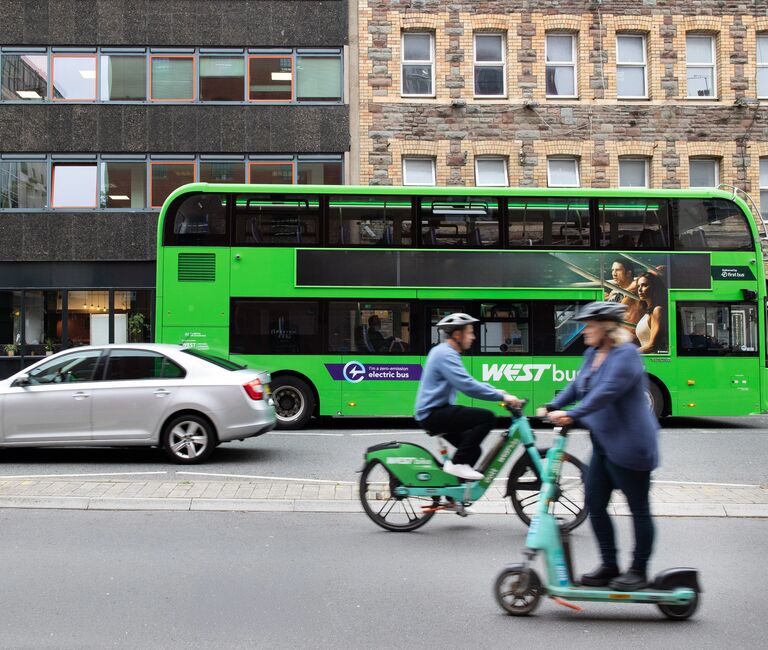 Bus, scooter, cyclist and car on the road