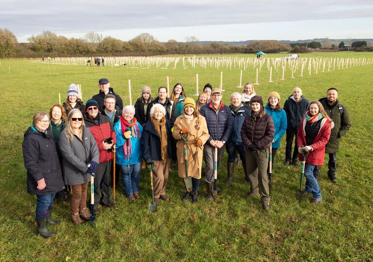 volunteers and partners stand in front of newly planted trees
