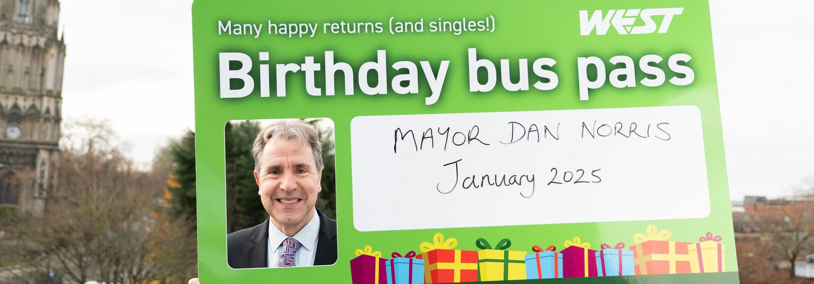 Mayor holding a sign up to his face which reads 
