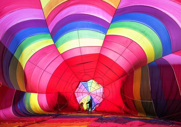 a person in front of a deflated rainbow hot air balloon