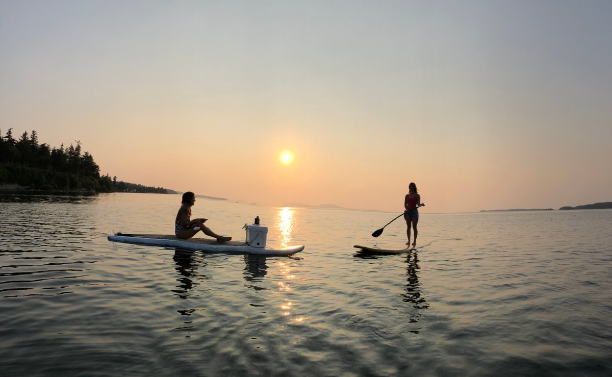 Friends picnicking during a sunset on paddle boards