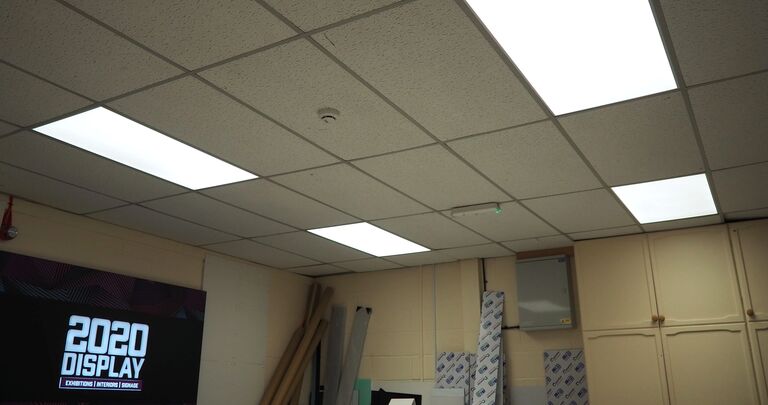 view of a room with ceiling tiles, square lights, and a television screen
