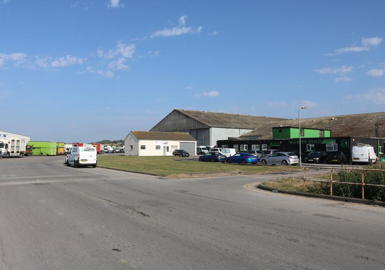 view of warehouse, road and vehicles against blue sky