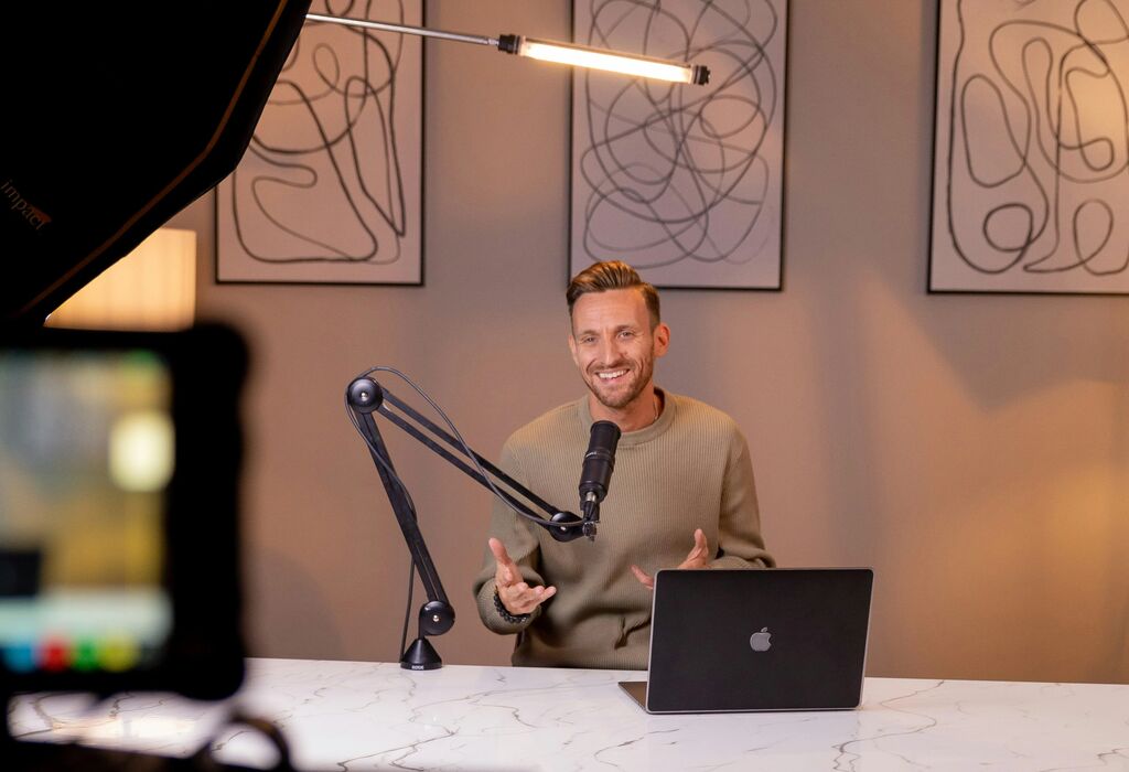 Person working at laptop, creating video with a microphone