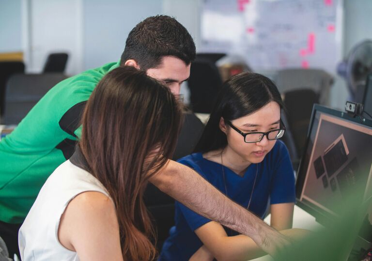 Three people pointing at screen