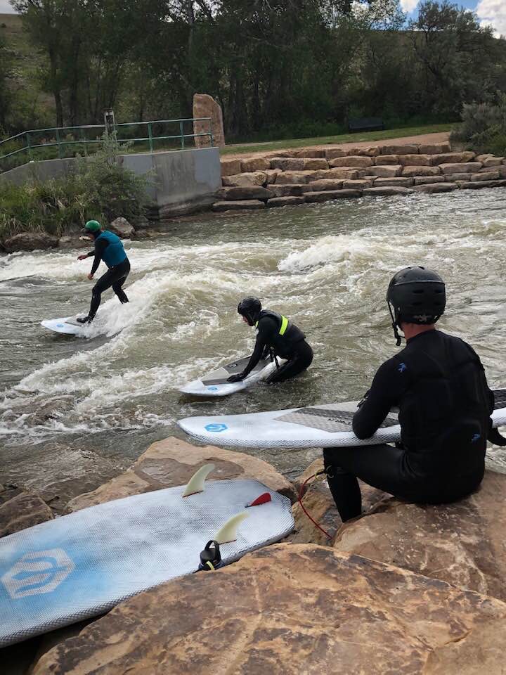 group surfing a river wave