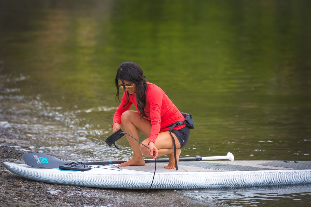 woman setting up her paddle board with leash