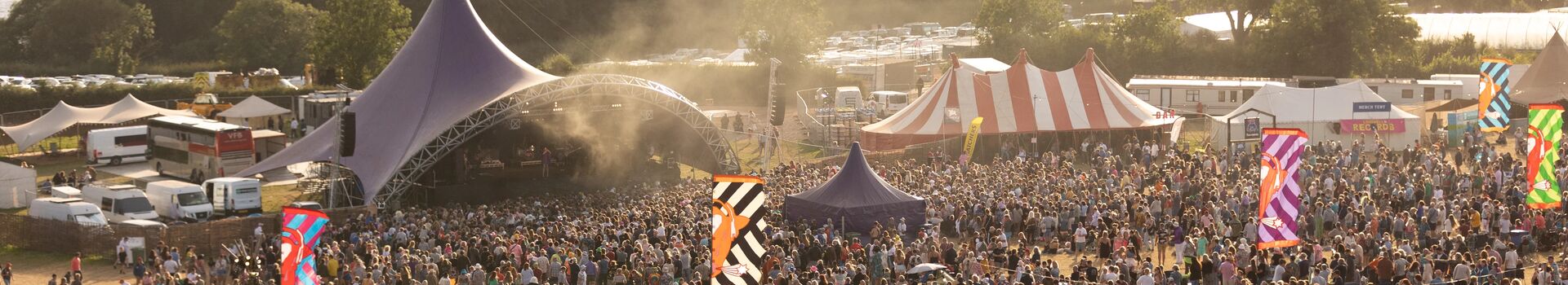 A festival at sunset, music tents and crowds